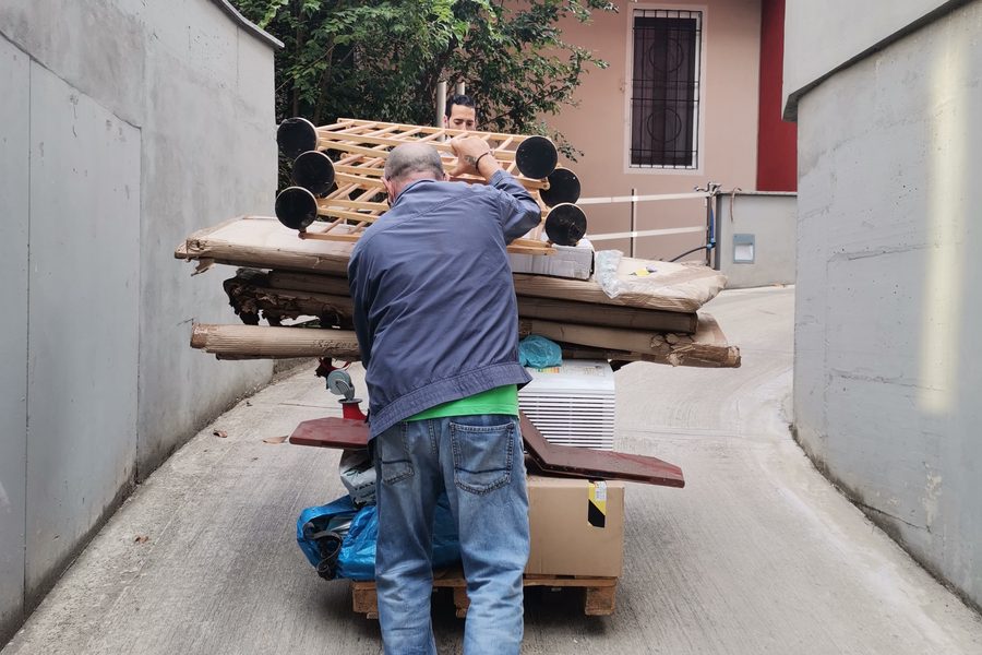 Mitarbeiter transportiert Sperrgut mit einem Wagen ab