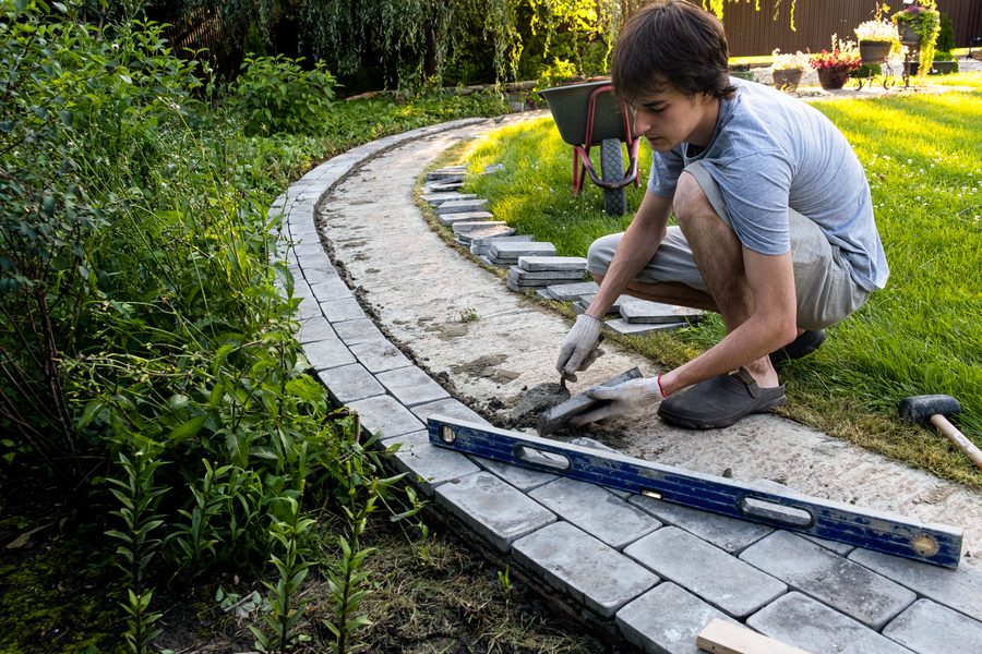 Gartenweg wird mit Pflastersteinen verlegt